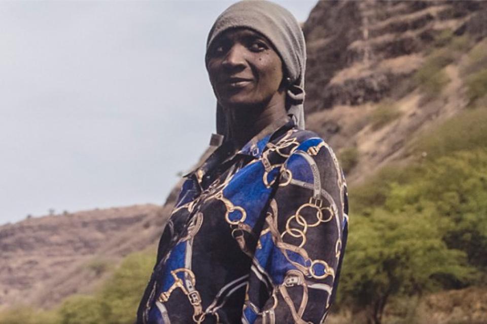 Retrato de uma mulher de lenço na cabeça, numa paisagem de montanha