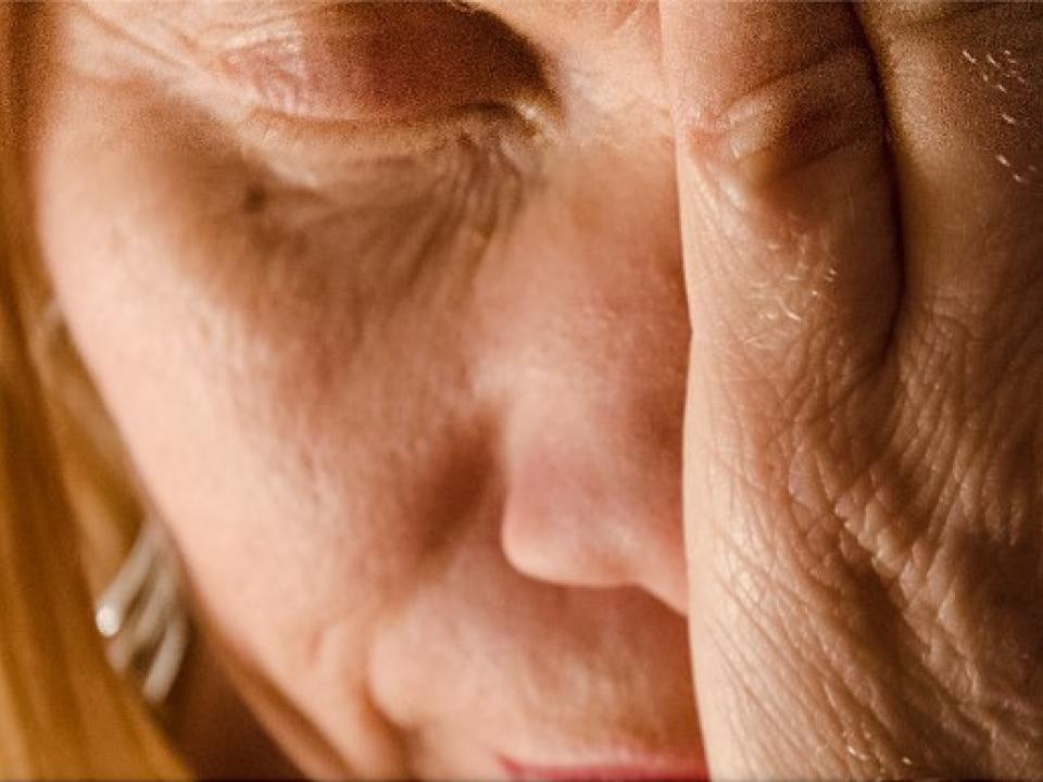 Grande plano de um rosto de olhos fechados, com a mão encostada à face